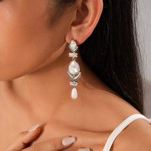 Detailed view of silver dangle earrings with crystals and teardrop pearls on a model