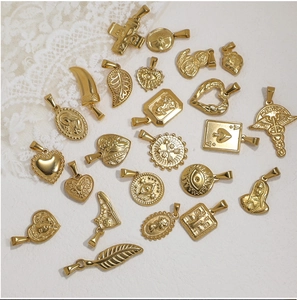 Close-up of assorted vintage 24K gold plated stainless steel pendants on white lace