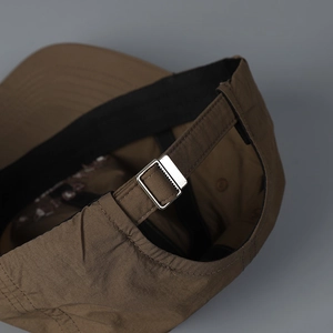 Macro detail of dark brown baseball cap featuring adjustable silver metal buckle and strap