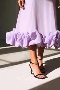 Detail of light purple midi dress featuring wide ruffled hemline and tiered layers