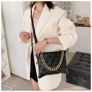 Detail of black woven leather shoulder bag featuring a chunky gold chain and flap closure