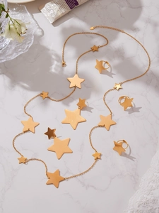 Flat lay of gold star jewelry set with necklace earrings and rings on marble