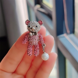 Macro detail of cute teddy bear brooch with pink crystals and a hanging pearl drop