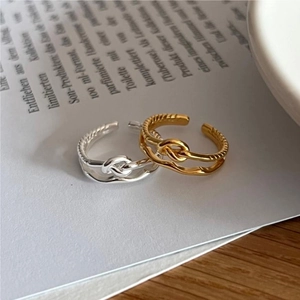 Close-up of twisted rope knot open rings in gold and silver finish on vintage paper