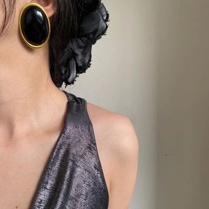 Close-up of vintage large black oval earrings with a gold metal frame on a fashion model