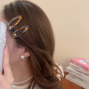 Close-up of elegant acetate amber oval hair clips and pearl jewelry worn by a model