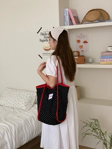Detail of canvas tote bag with polka dot print, red handles and Future woven label