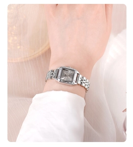 Elegant silver square quartz watch with steel chain strap on white silk fabric