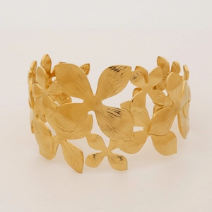Detailed close-up of golden hollow flower pattern on wide stainless steel cuff bracelet