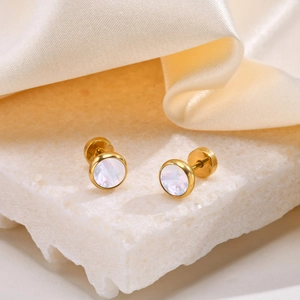 Macro shot of gold stainless steel stud earrings with iridescent pearl inlay on stone