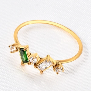 Macro de bague dorée avec pierre verte taille émeraude et détails en zircone cubique