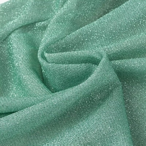 Close-up detail of green fabric with shimmering glitter finish and soft elegant draping