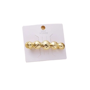 Elegant golden alloy hair clip with spherical design on a white branded card