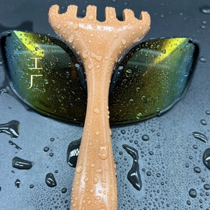 Detail of five-claw resin massage scraper with faux wood grain texture on dark surface