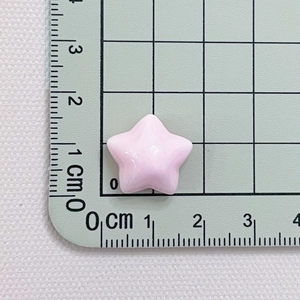 Macro shot of a 1cm pink resin star accessory on a green measurement cutting mat