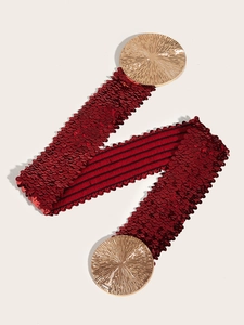 Close-up of red sequins elastic wide belt with large textured gold metal circle buckles