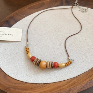 Détails d'un collier ethnique fait main avec des perles en bois et un pendentif cœur