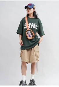 Detailed view of candy-colored PVC crossbody bag with orange strap worn by female model