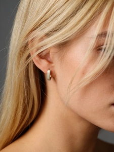 Close-up of minimalist gold matte square hoop earrings worn by a model in a side view