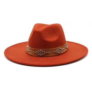 Dettaglio cappello fedora arancione in feltro con fascia in pelle e borchie argento