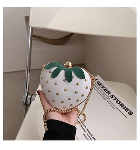 Close-up of ivory strawberry shaped mini bag with gold rivets and leaf detail