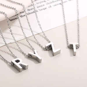 Close-up of four silver stainless steel alphabet necklaces with R, Y, Z, and T pendants