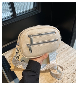 Detail der beigefarbenen Leder-Brusttasche mit Doppelreißverschluss und Web-Schultergurt