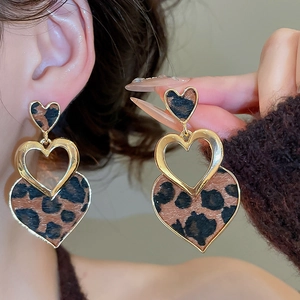 Detail showing vintage leopard print heart earrings with gold metal frame on model