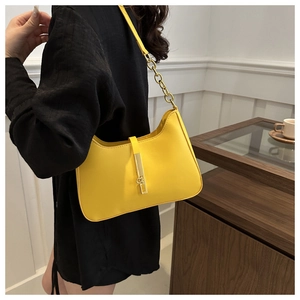 Detail of yellow leather underarm bag with gold chunky chain strap and metallic buckle