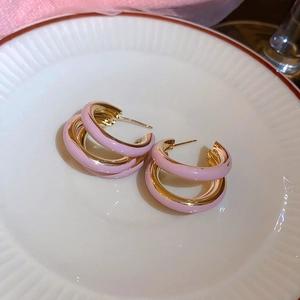 Dettaglio di orecchini a fiore in smalto rosa e oro su un piatto decorativo bianco