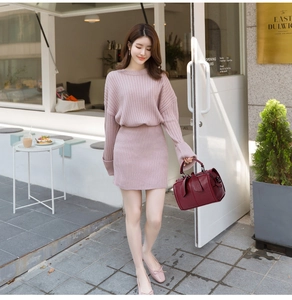 Detailaufnahme eines rosa Strickkleides mit roter Handtasche in einer Café-Szene