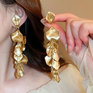 Macro shot of gold tassel earrings featuring layered metal rose petals and dangling fringe