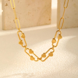 Elegant gold stainless steel heart necklace with paperclip chain on warm stone background