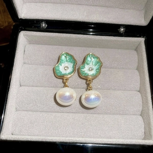 Macro detail of French vintage pearl floral earrings with green enamel and gold finish