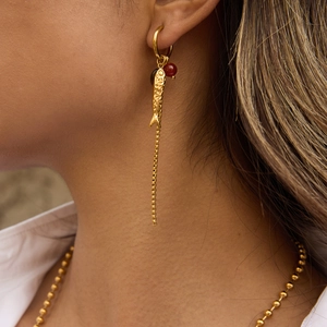 Elegant gold fish tassel earrings with red bead and long chain on model