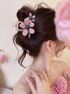Close-up of a pink floral hair claw clip worn in a stylish bun on a model
