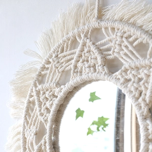 Close-up of handmade macrame fringe and intricate knot texture on round wall mirror