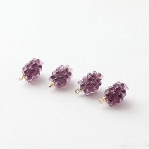 Detailed view of four purple resin grape pendants with gold loops for DIY jewelry making