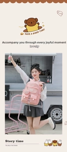 Detailed view of pink water-resistant nylon backpack with utility pockets and charm