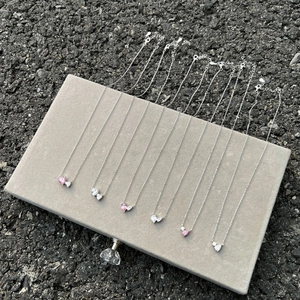 Detail of pink and white pear-shaped zircon heart necklaces on grey velvet case