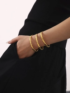 Close-up of three-piece 18K gold plated stainless steel snake bone bracelets on wrist