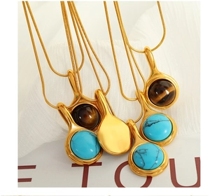 Macro shot of gold pendant necklaces with blue turquoise and brown tiger eye stone inlay