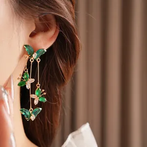 Boucles d'oreilles papillon dorées avec zircons verts et blancs et pampille élégante