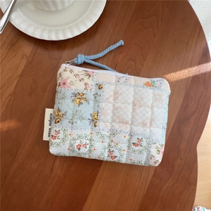 Detail of floral quilted cotton pouch featuring simple wish label and soft zipper puller