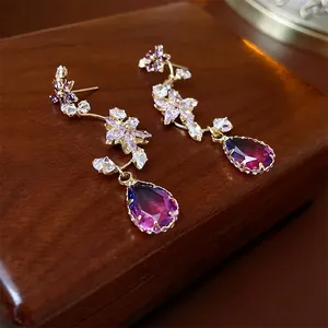 Elegant gold earrings with purple cubic zirconia flowers and pear-cut crystal teardrops