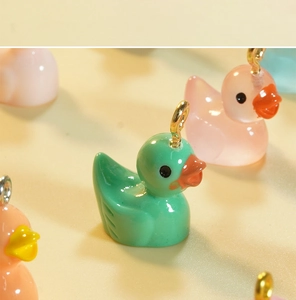 Macro detail of colorful resin duck charms with glossy finish and metal eyelet hooks