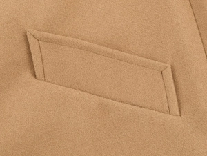 Macro view of the camel wool blend coat showing refined stitching detail and pocket design