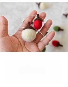 Handheld close-up showing the scale of colorful handmade wool felt acorn garland decor