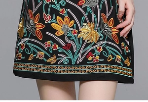 Close-up of heavy floral embroidery and scalloped edges on a black designer dress
