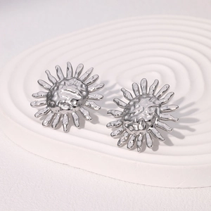 Orecchini a perno a forma di girasole in metallo martellato su supporto bianco di design